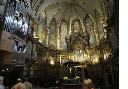  Photo shows the inside of an ornate beautiful church with a huge set of organ pipes on one wall.